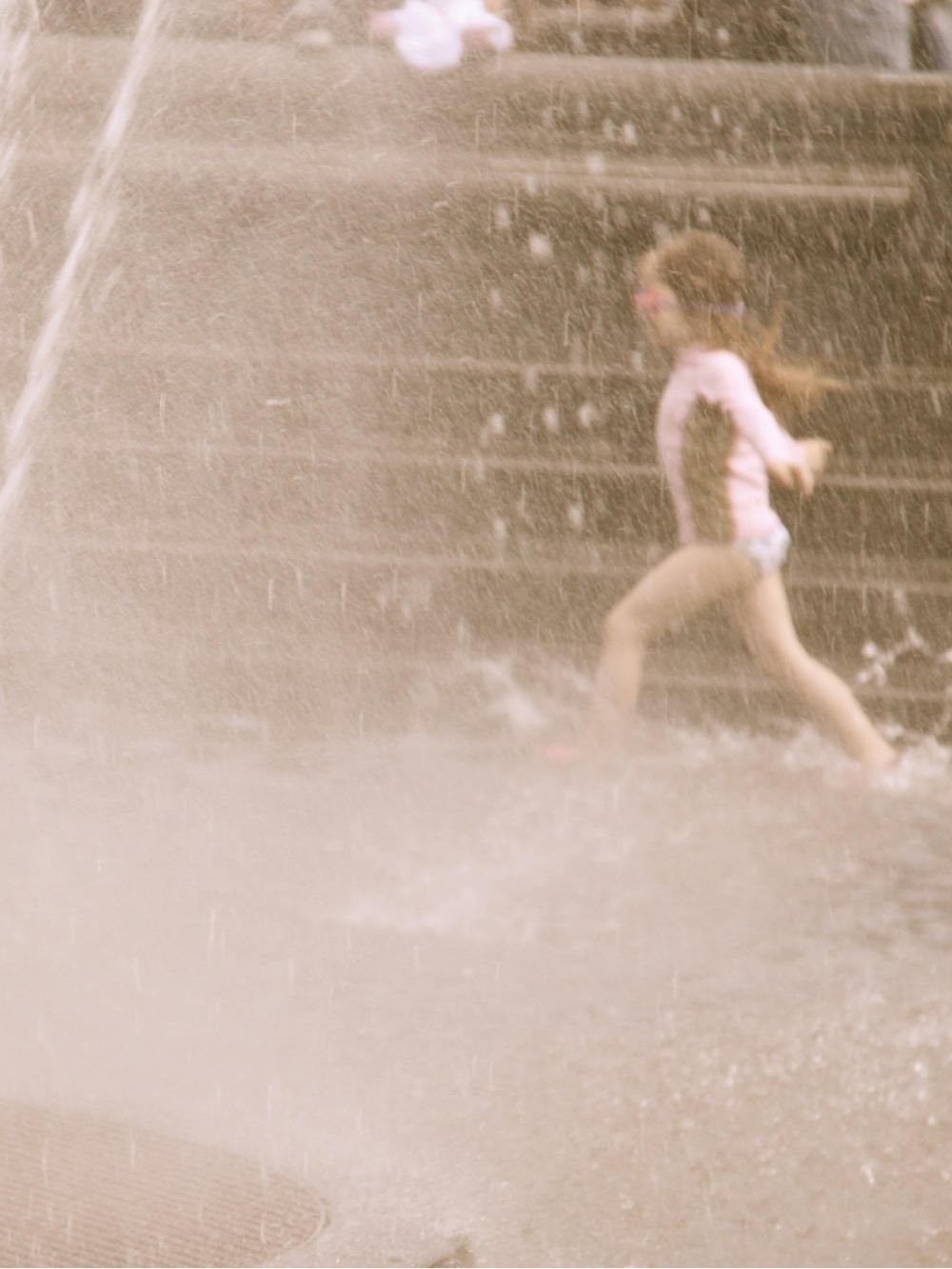 Photograph of a girl running through sprinklers in NYC - Washington Square Park